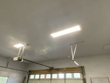 Brightly lit garage ceiling with modern LED lights and garage door opener.
