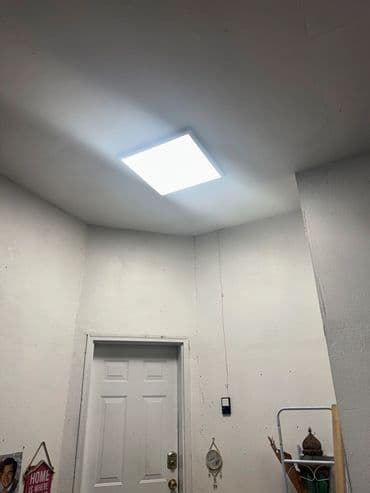 Bright ceiling light in a corner room with a door and decorative wall elements.