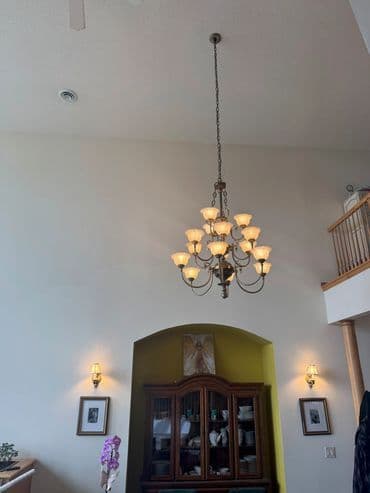 Elegant chandelier hanging in a spacious foyer with decorative wall accents.
