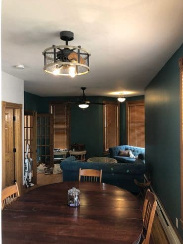 Modern dining area with wooden table, industrial light fixture, and blue couch in cozy interior.